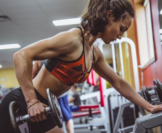 Woman doing a dumbbell row in a bright gym